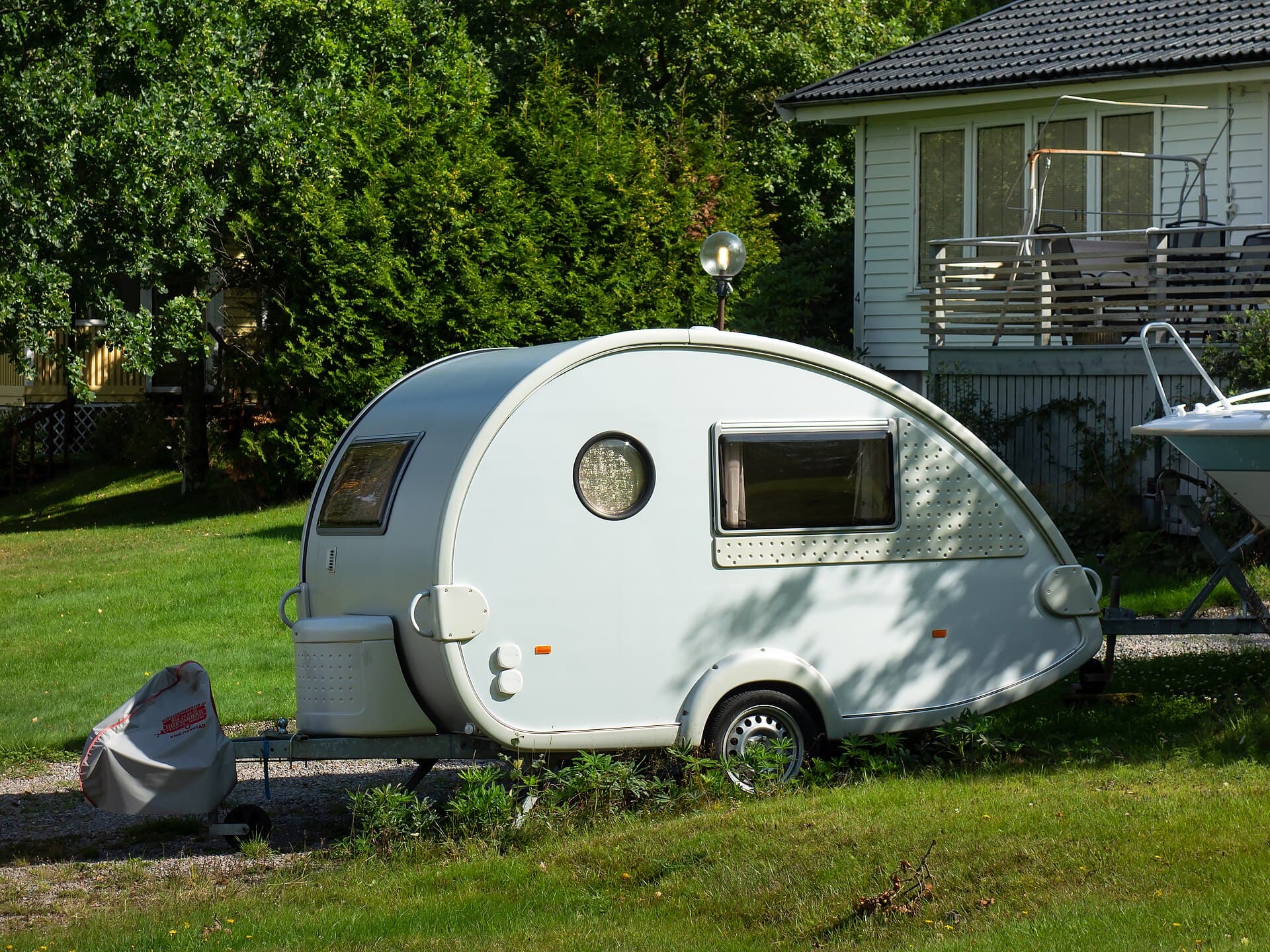 Off-road camper trailer on a dirt track with a compact hard-top body and off-road tyres